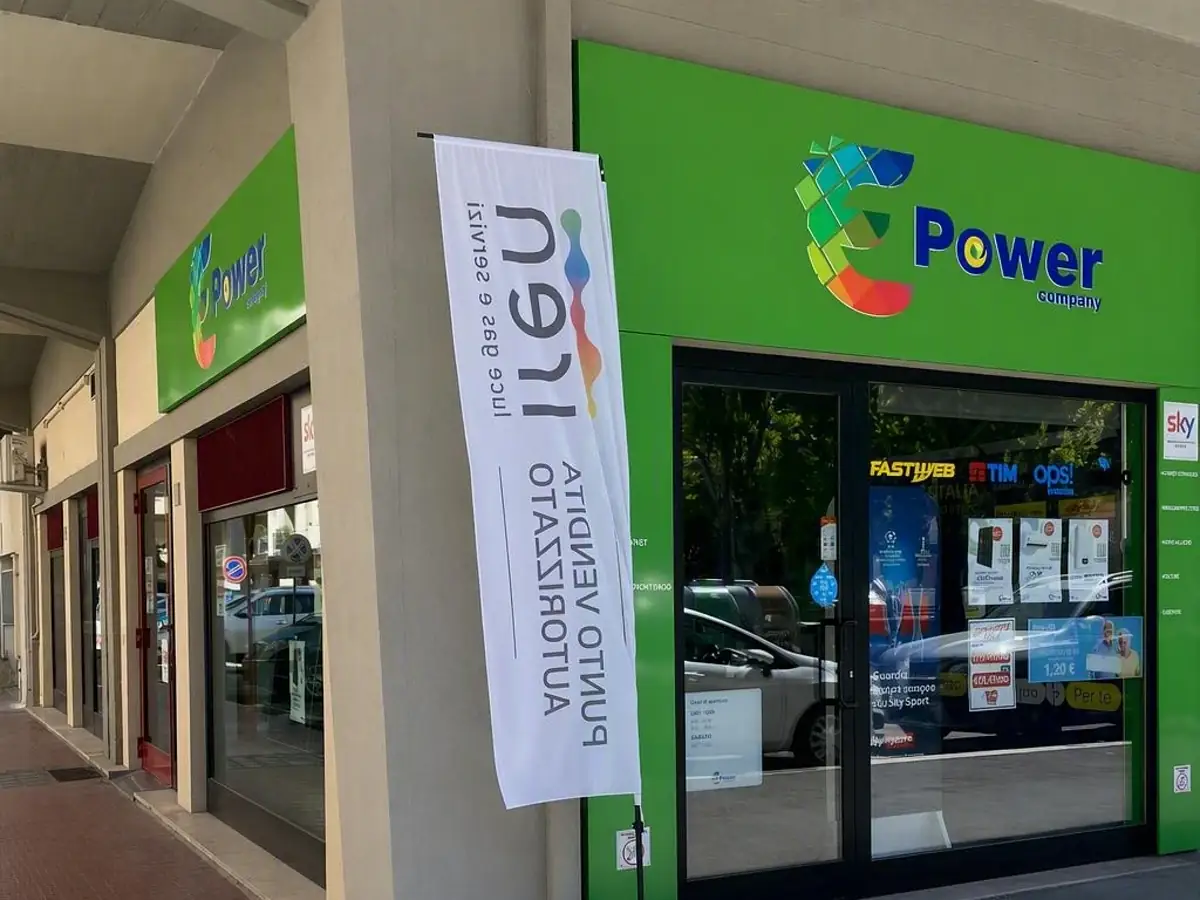 Il negozio E-Power Company di Piazza Giotto ad Arezzo: insegna verde sull'angolo sotto i portici, con la vela IREN davanti all'ingresso